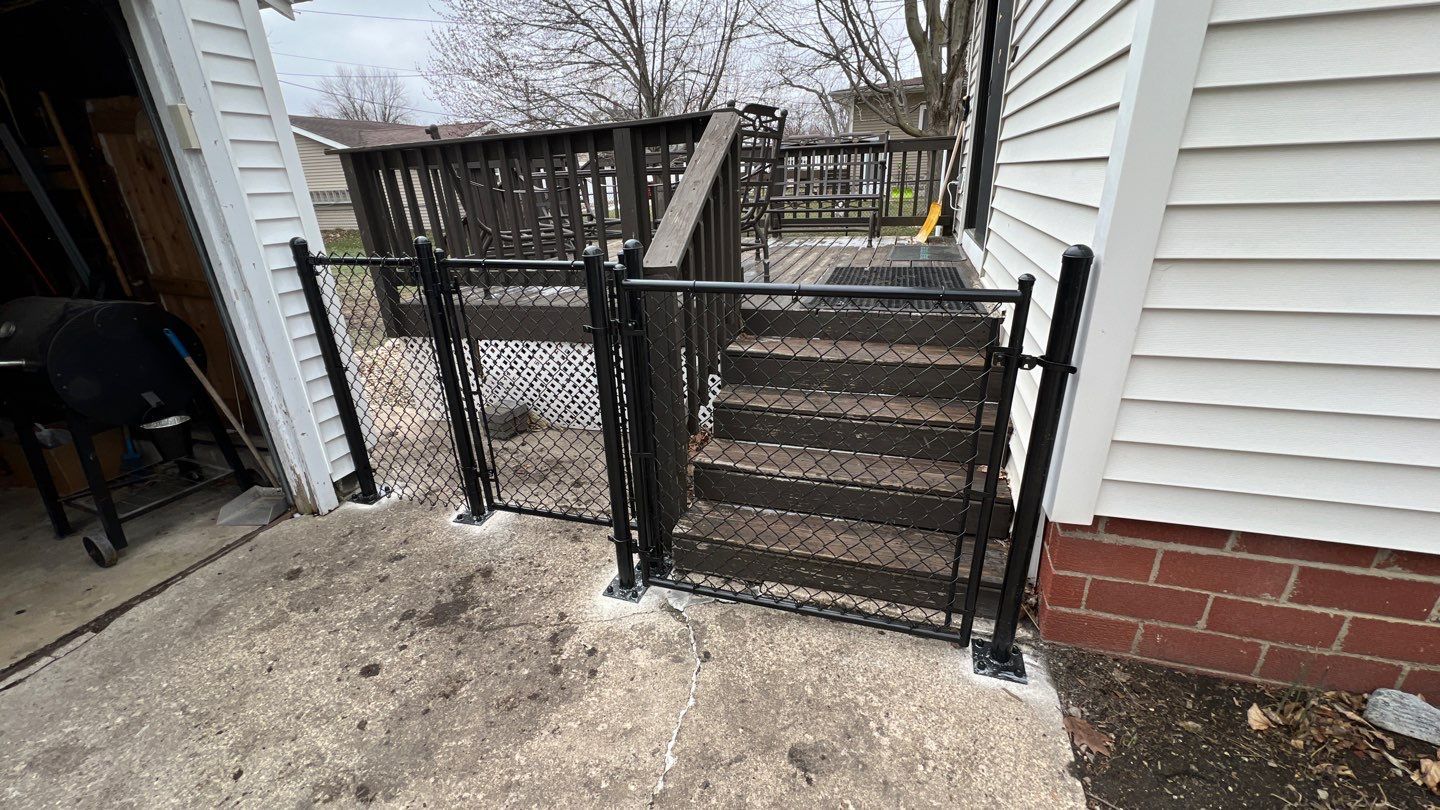Black chain-link safety gates installed beside concrete steps leading to a raised wooden deck. Black chain-link safety gates installed beside concrete steps leading to a raised wooden deck.