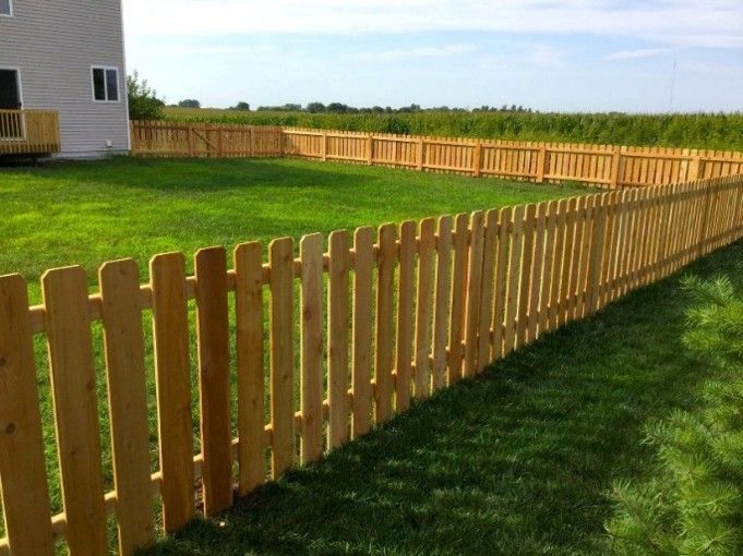 Wooden picket fence surrounding a residential backyard and lawn