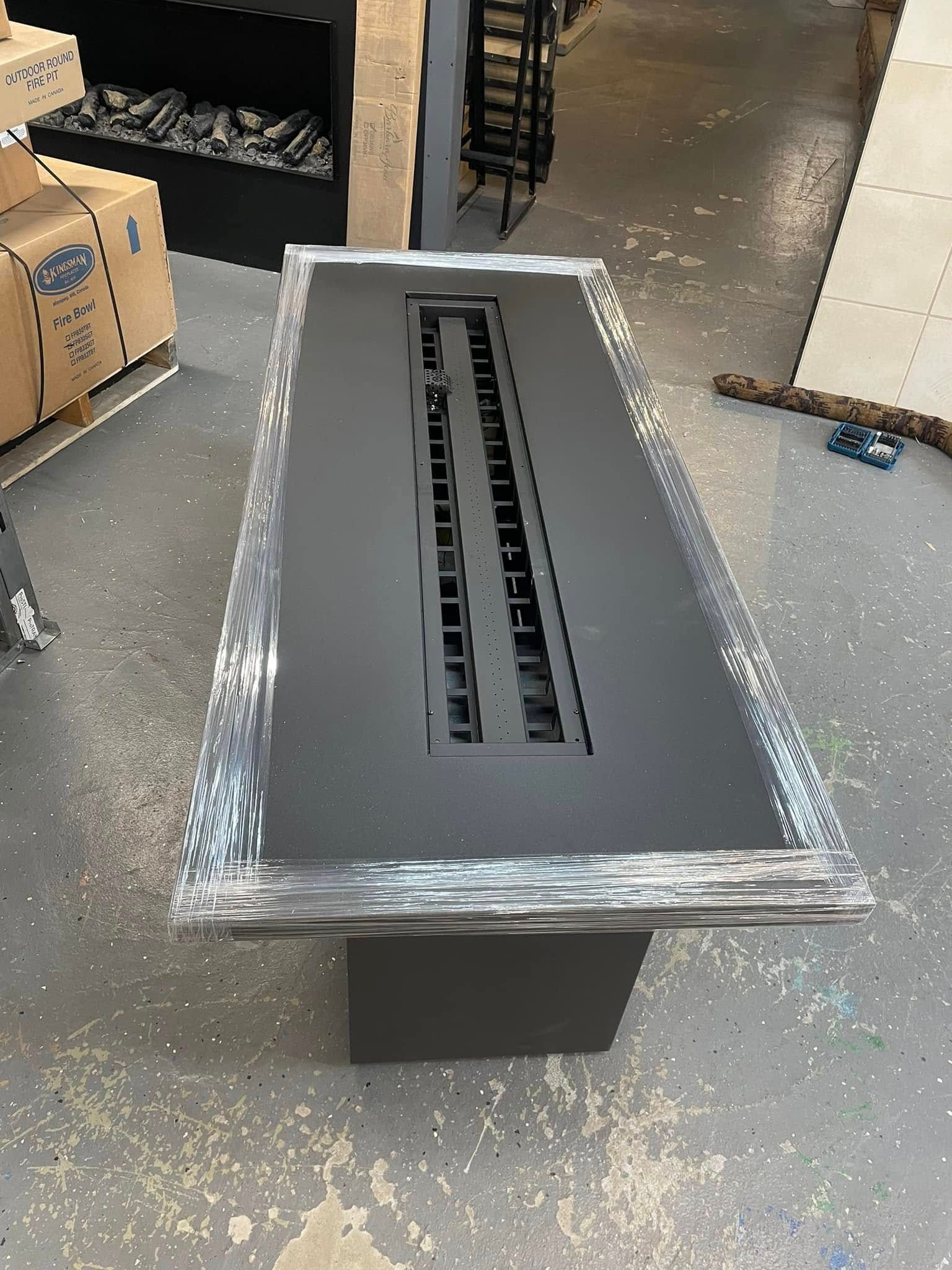 Rectangular outdoor fire pit with a dark surface and a gray base.