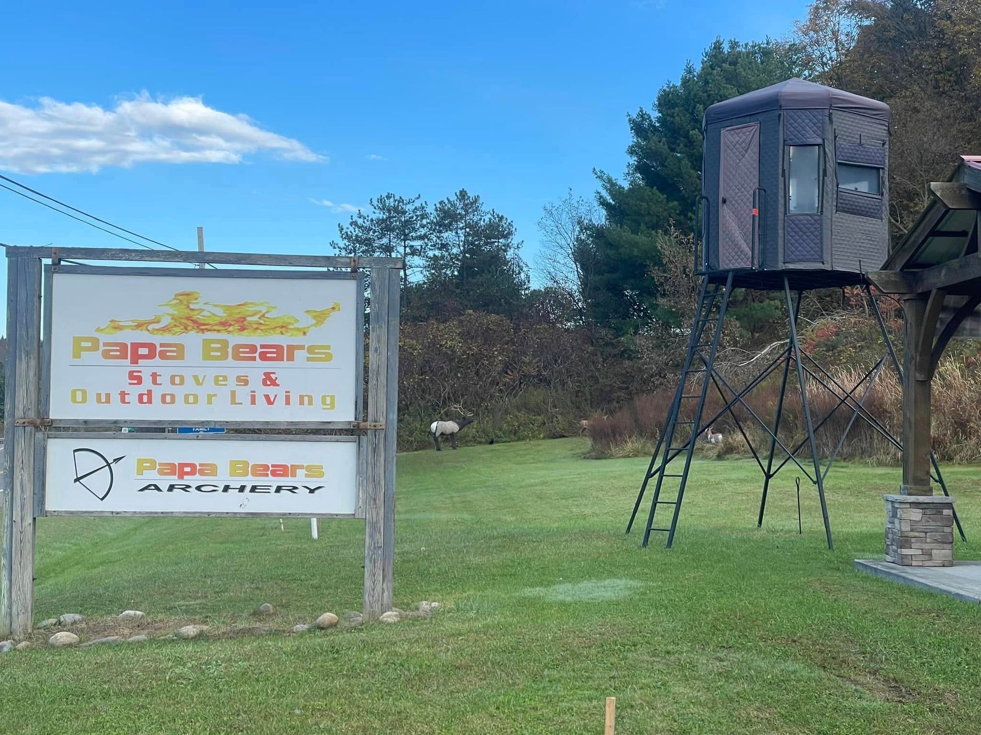 Sign for Papa Bears, an outdoor store, with an archery range and elevated hunting blind.