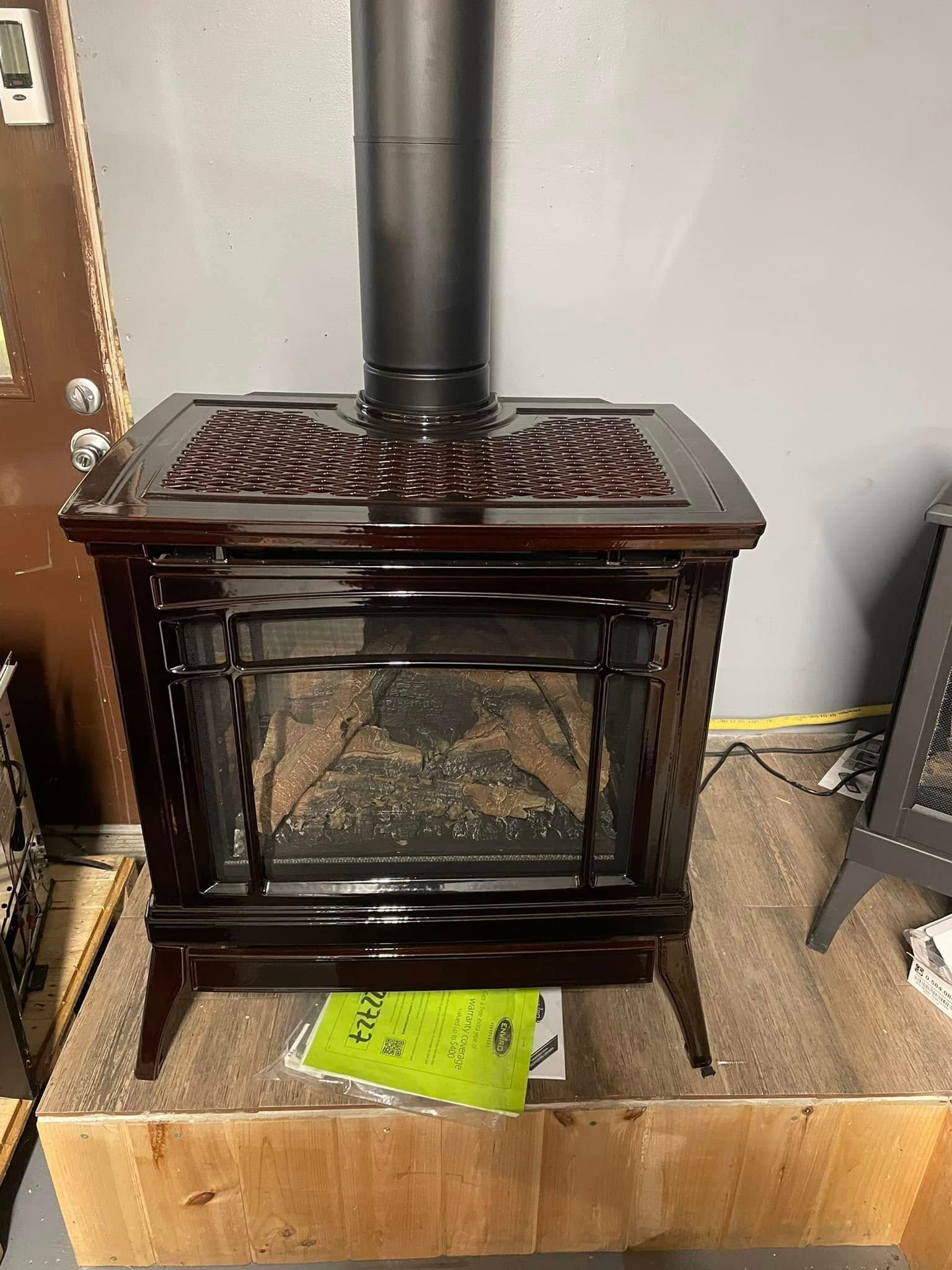Dark brown gas fireplace with black chimney in a room.