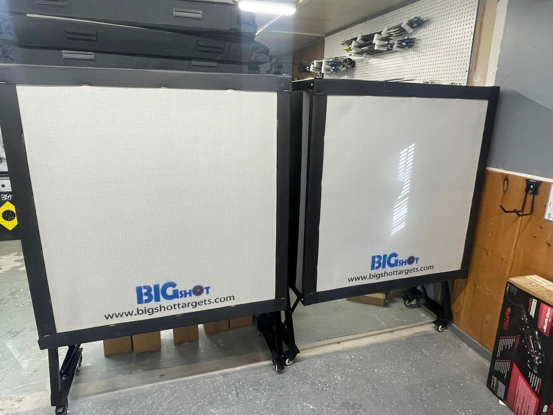 Two large, square, white projector screens with black frames and stands; 
