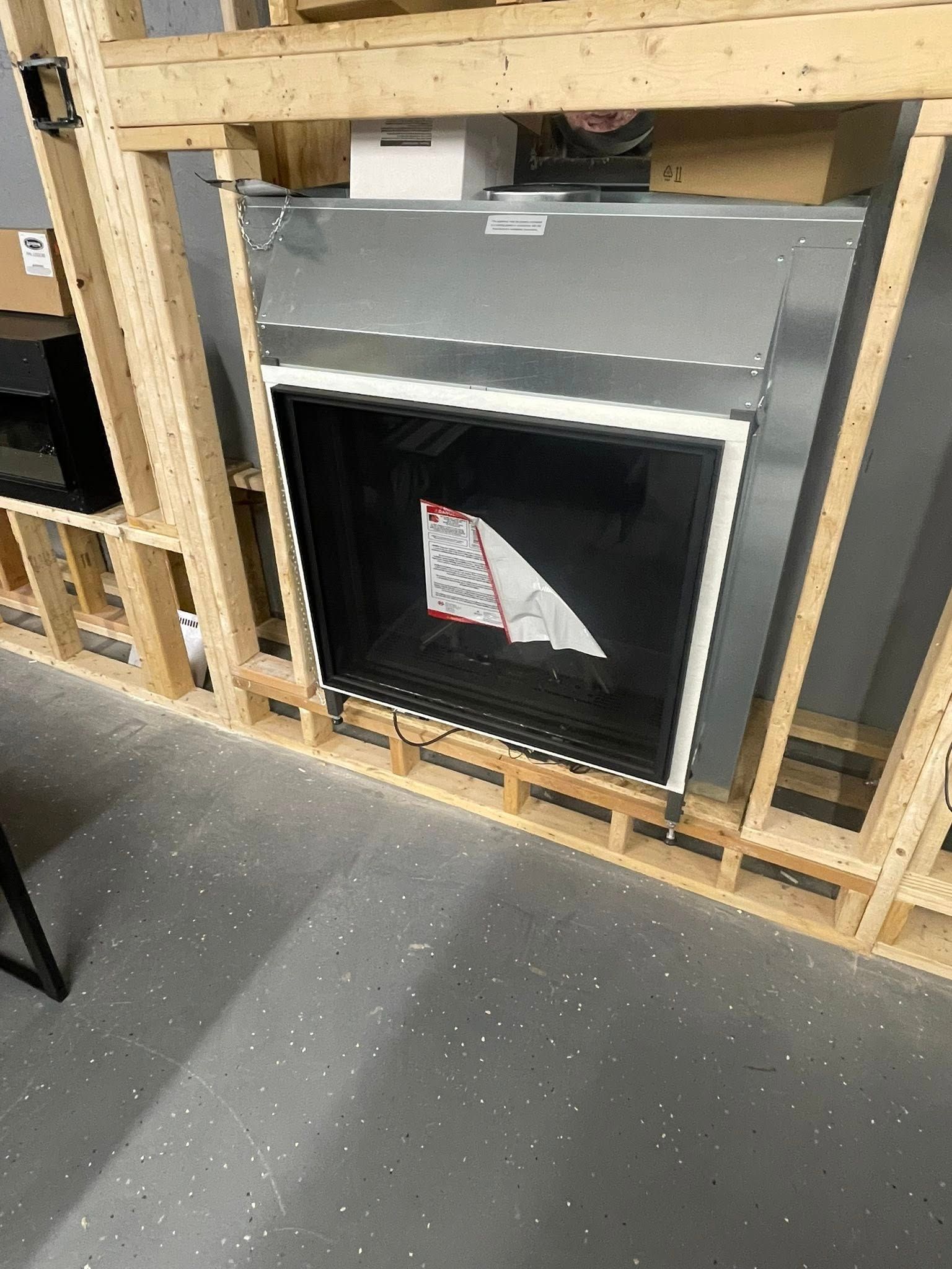 A fireplace installed within a wooden frame, featuring a black viewing area and silver exterior.