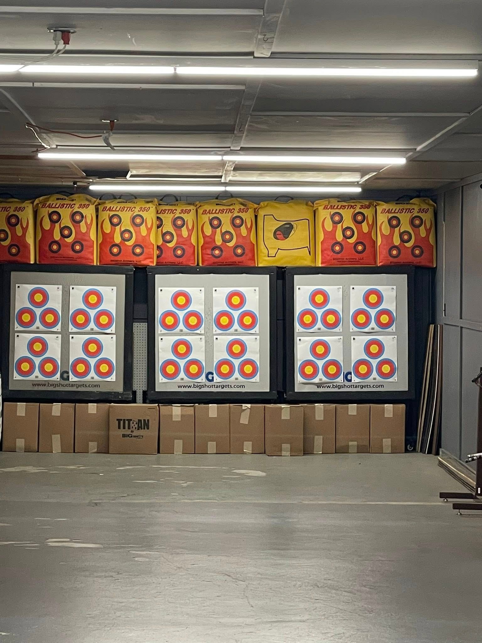Archery range: Targets on wall, boxes on floor, red/yellow/white target faces, in an indoor space.