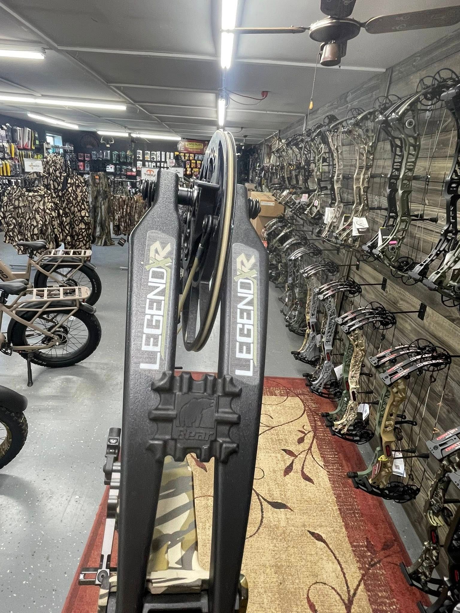 Black LEGEND archery bow stand inside a store with bows on display.