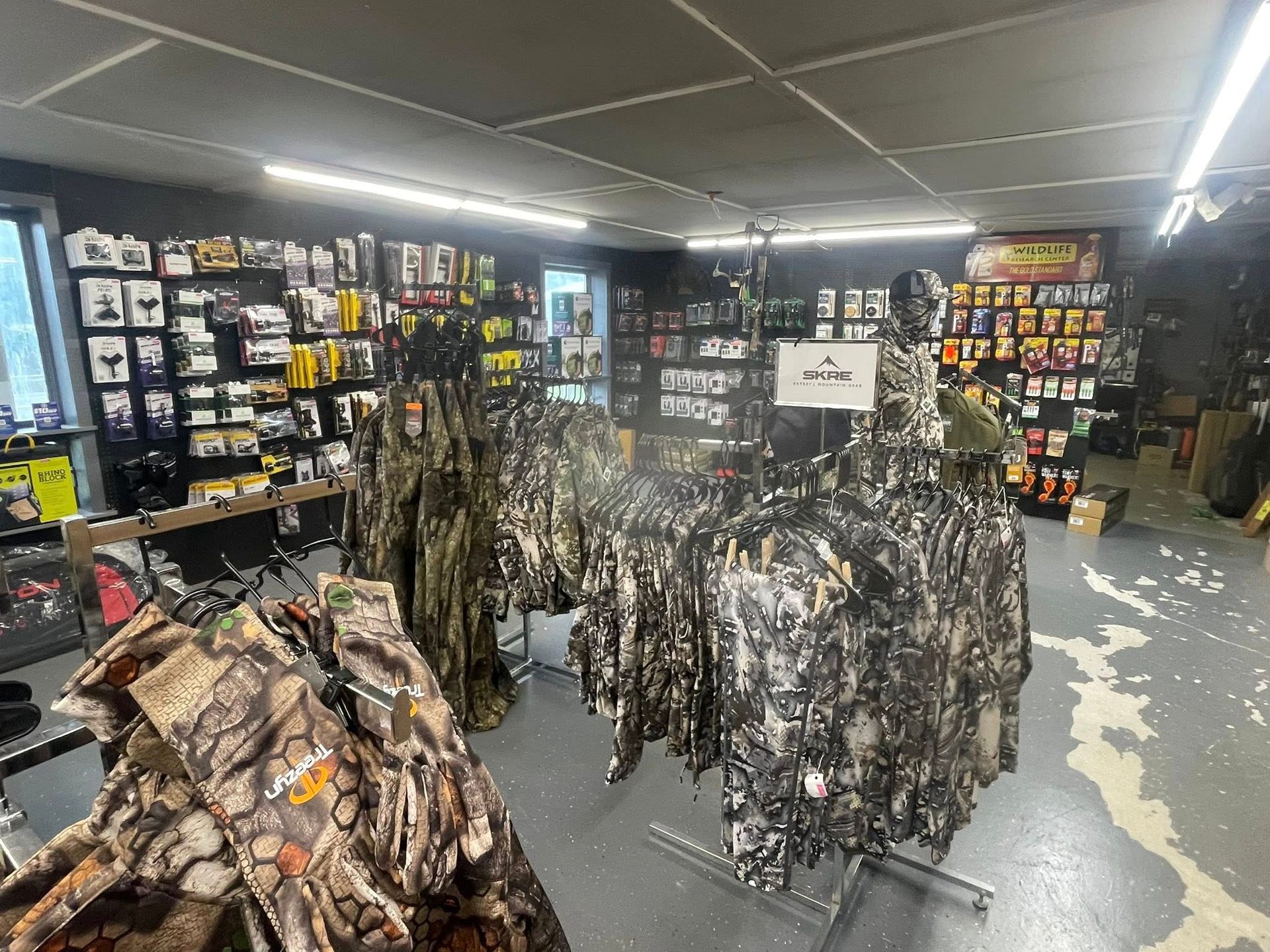 Inside a hunting supply store, camouflage clothing displayed on racks. Various hunting accessories on shelves.