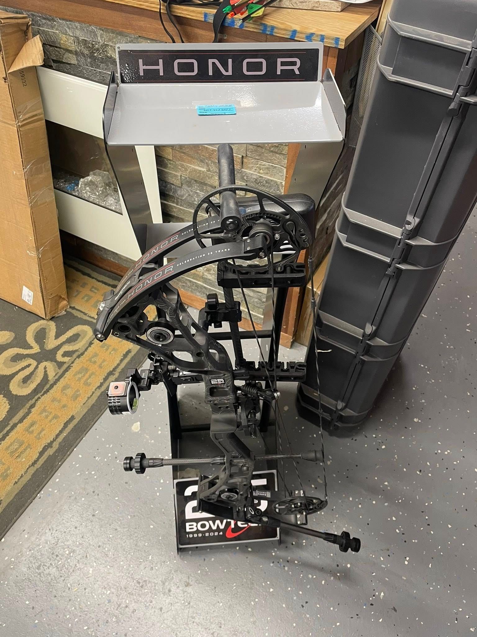 Compound bow in a tuning stand with a HONDR label in a workshop setting.