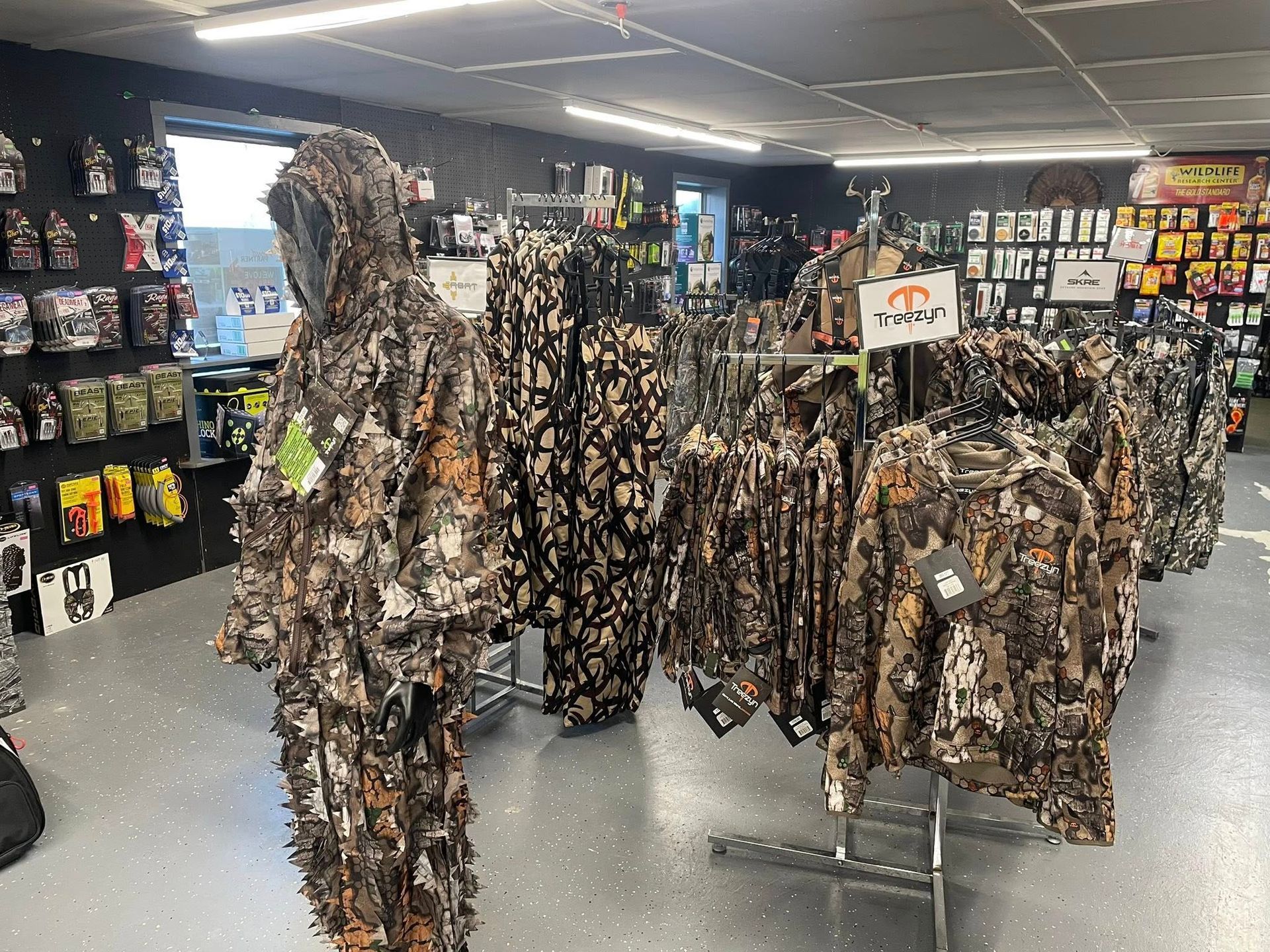 Hunting camouflage clothing display in a retail store. Brown and green patterns on racks and mannequins.