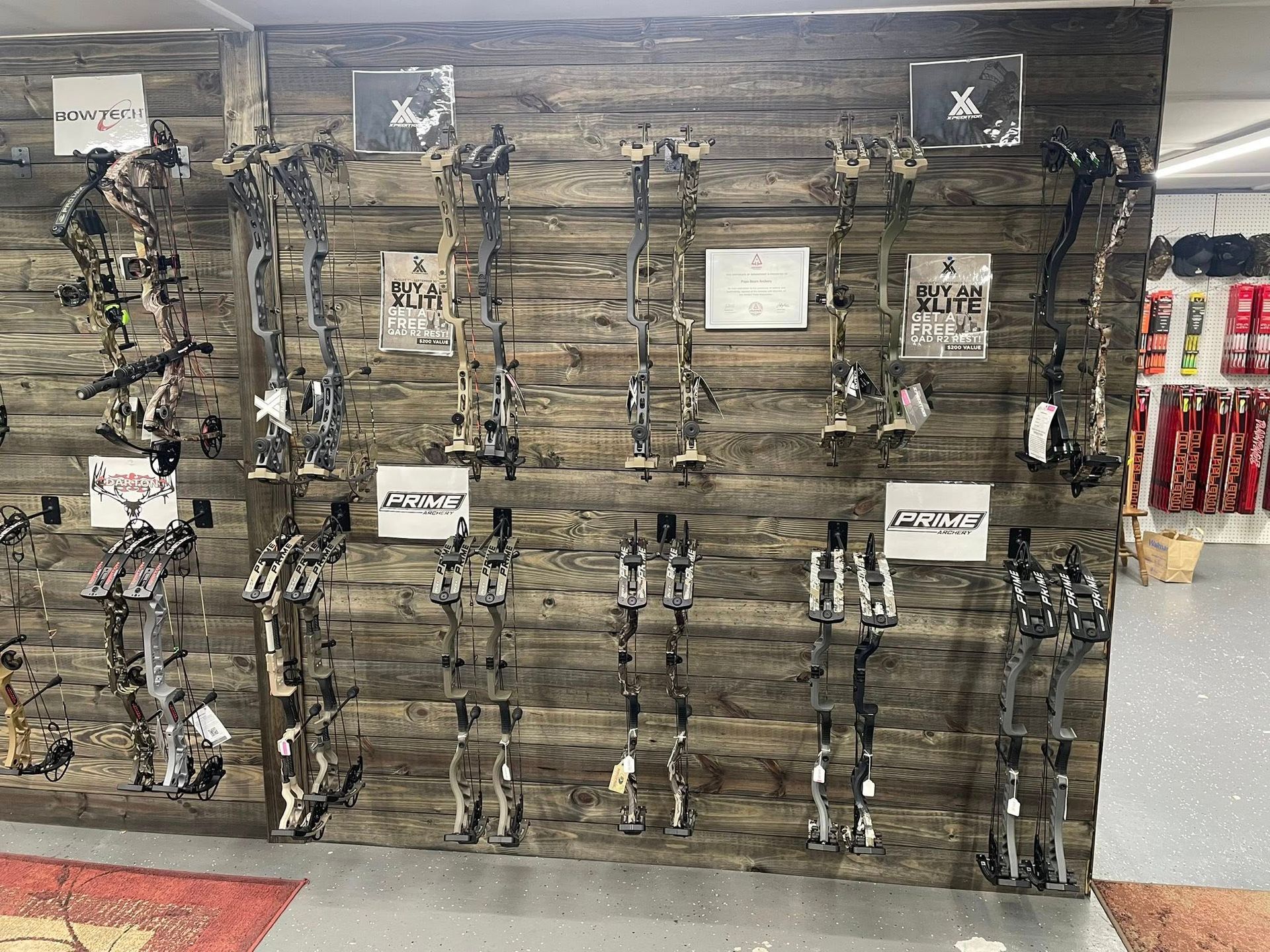 Archery equipment displayed on a wooden wall in a store.