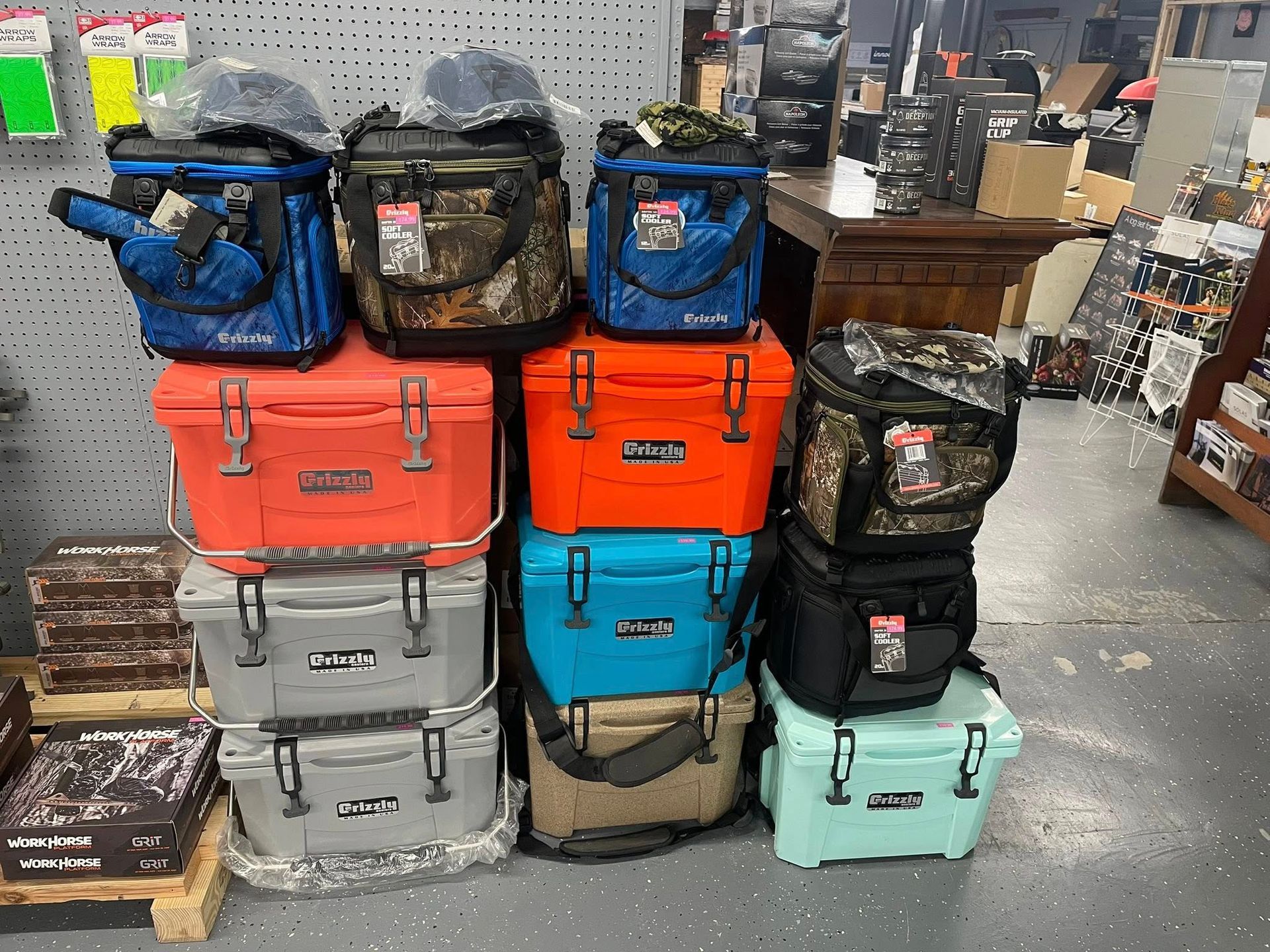 Coolers stacked in a retail setting, various colors and sizes.