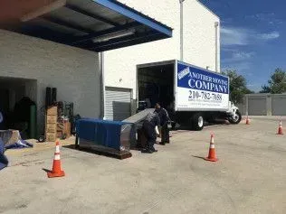Movers loading a large blue object onto a 