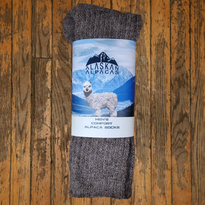 Brown alpaca socks rolled up, with a label featuring a Alpaca and mountains.