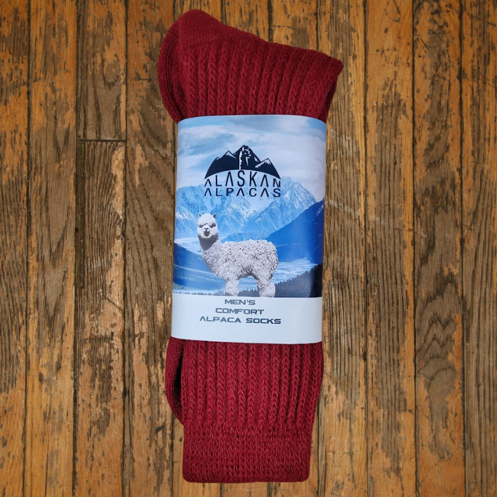 Red socks with Alaskan Alpaca label; alpaca and mountain scene.