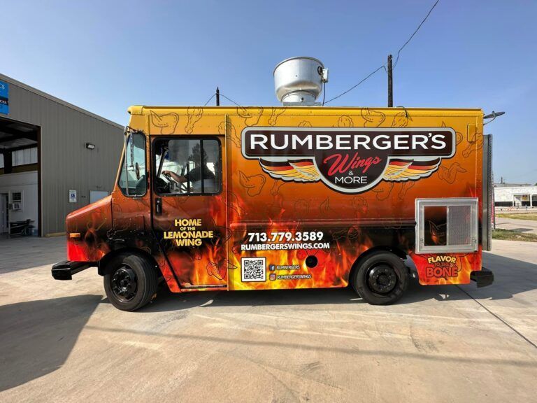 Rumberger's Wings & More food truck with a flame-patterned wrap, parked outdoors against a clear blue sky.
