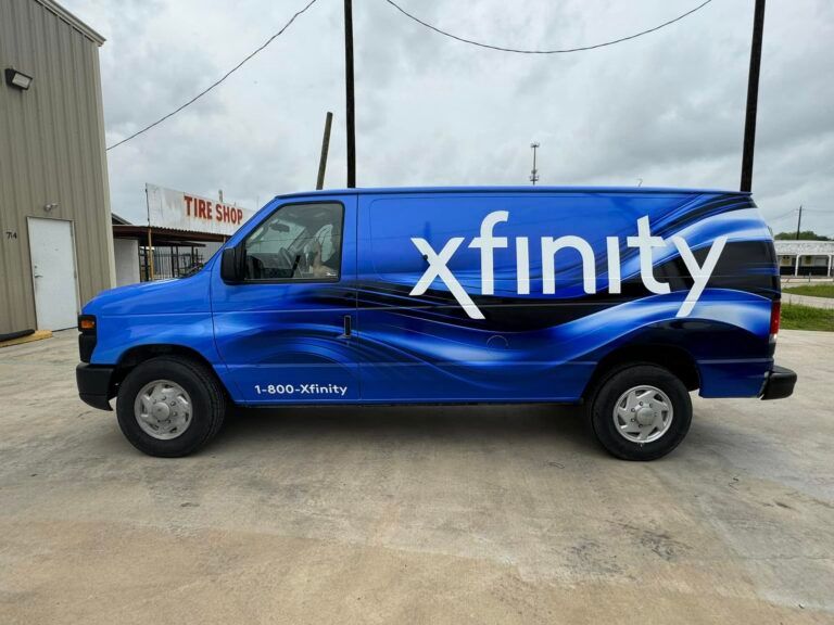 A blue Xfinity work van parked on a concrete lot next to a building.