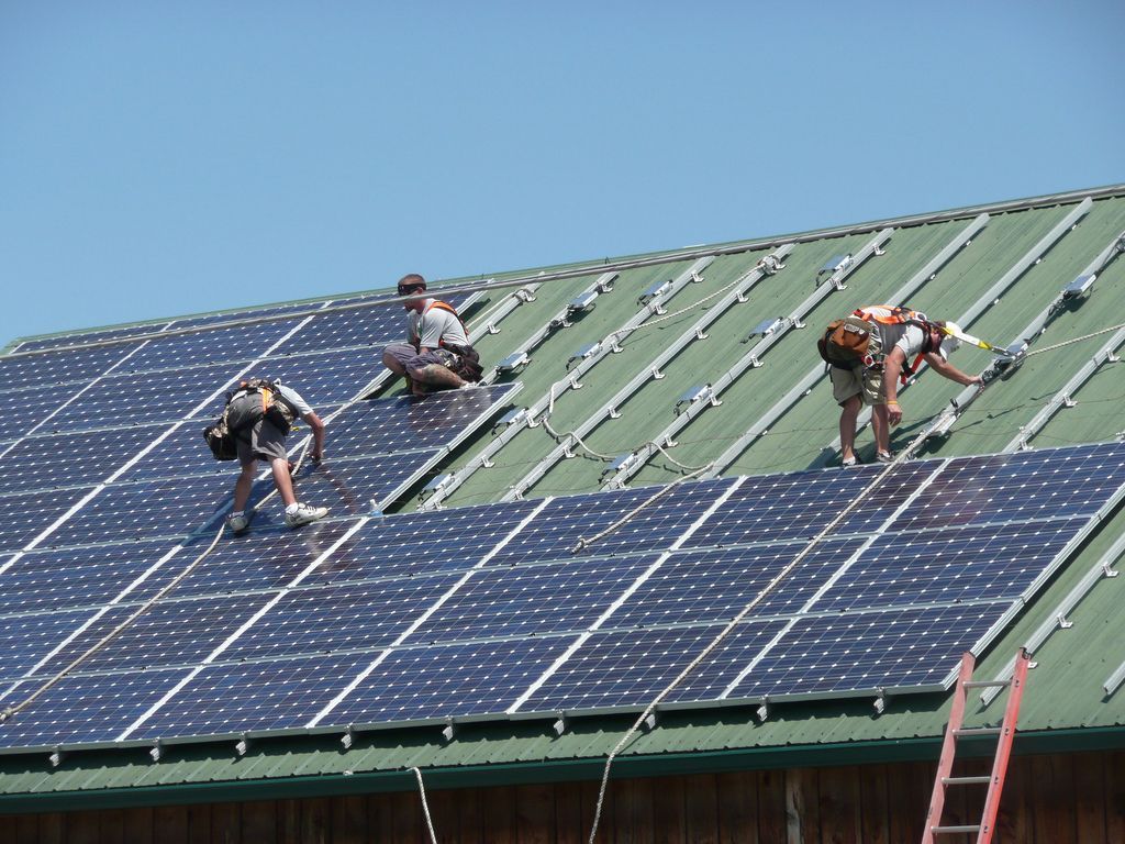 A photo of electricians installing solar panels on a roof