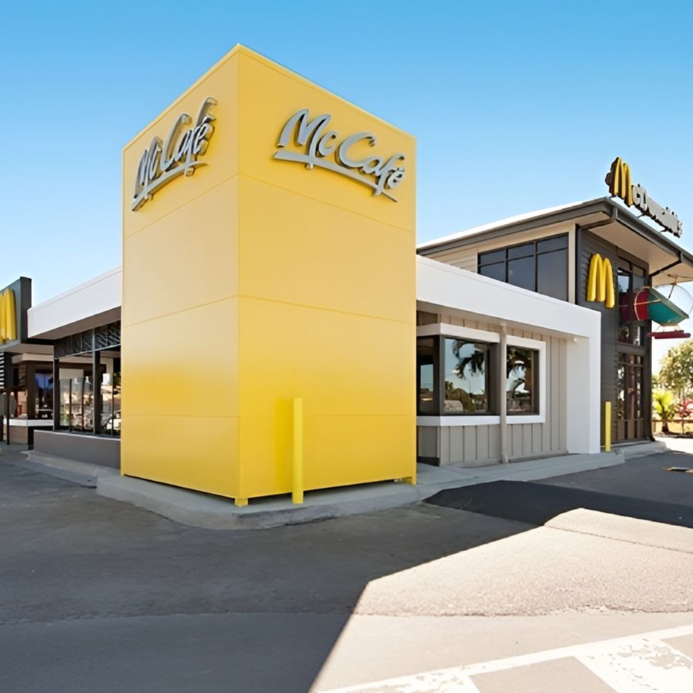 McDonald's restaurant with yellow accents, a McCafe sign, and a crosswalk on a sunny day— Nick Favot Painting In Bohle, QLD