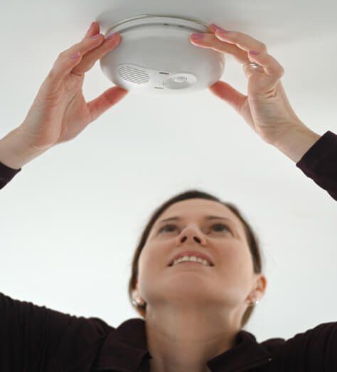 woman checking smoke detector