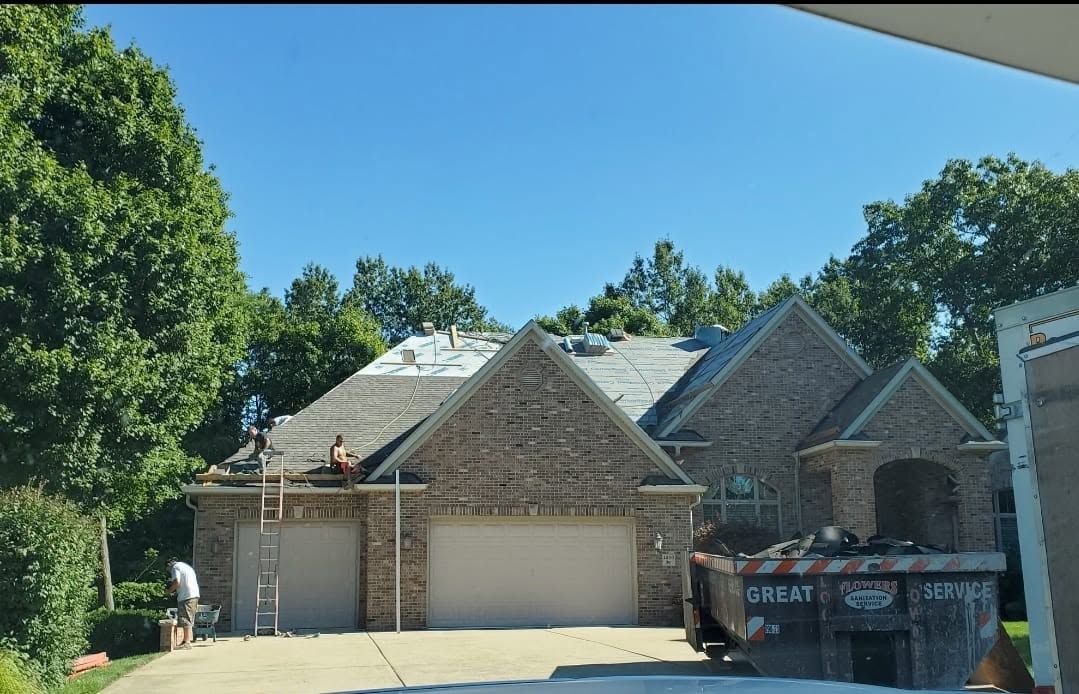 Brick suburban house with two garage doors, stone accents, and a blue sky on a sunny day