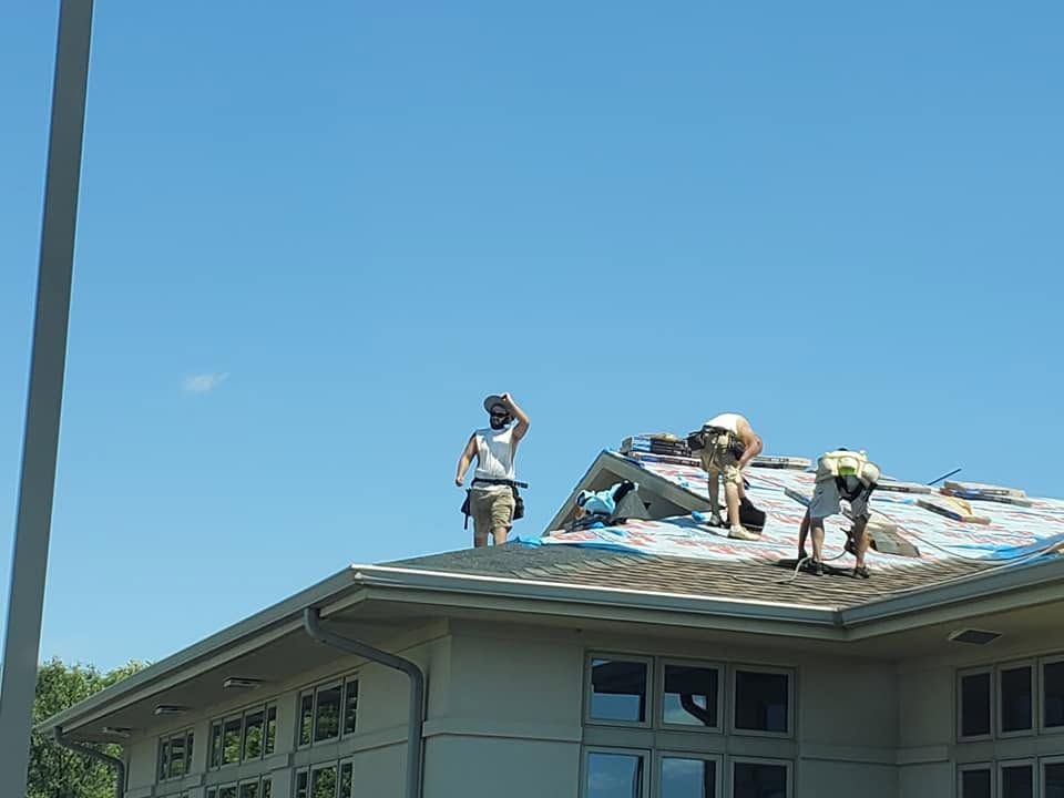Workers repairing a house roof under a clear blue sky
