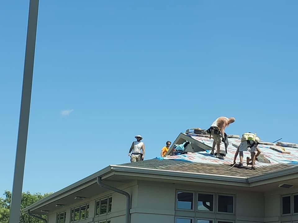 Roofers working on a house roof under a clear blue sky