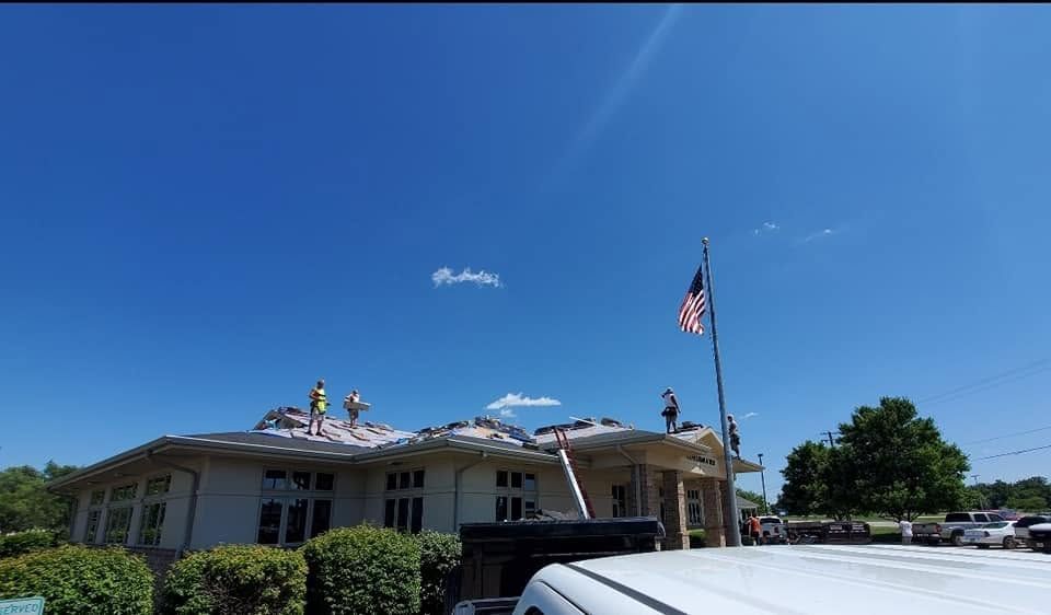 Single-story building under a clear blue sky, with an American flag and a car in front.