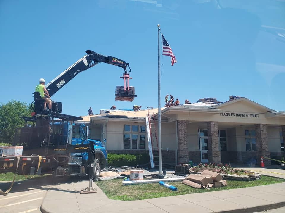 Crane lifts debris at a damaged building with an American flag and workers on site
