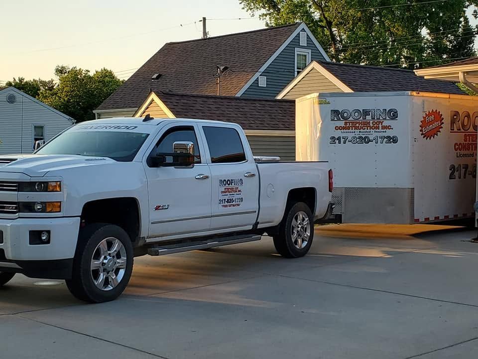 White pickup truck towing a white utility trailer parked in a suburban driveway at dusk.