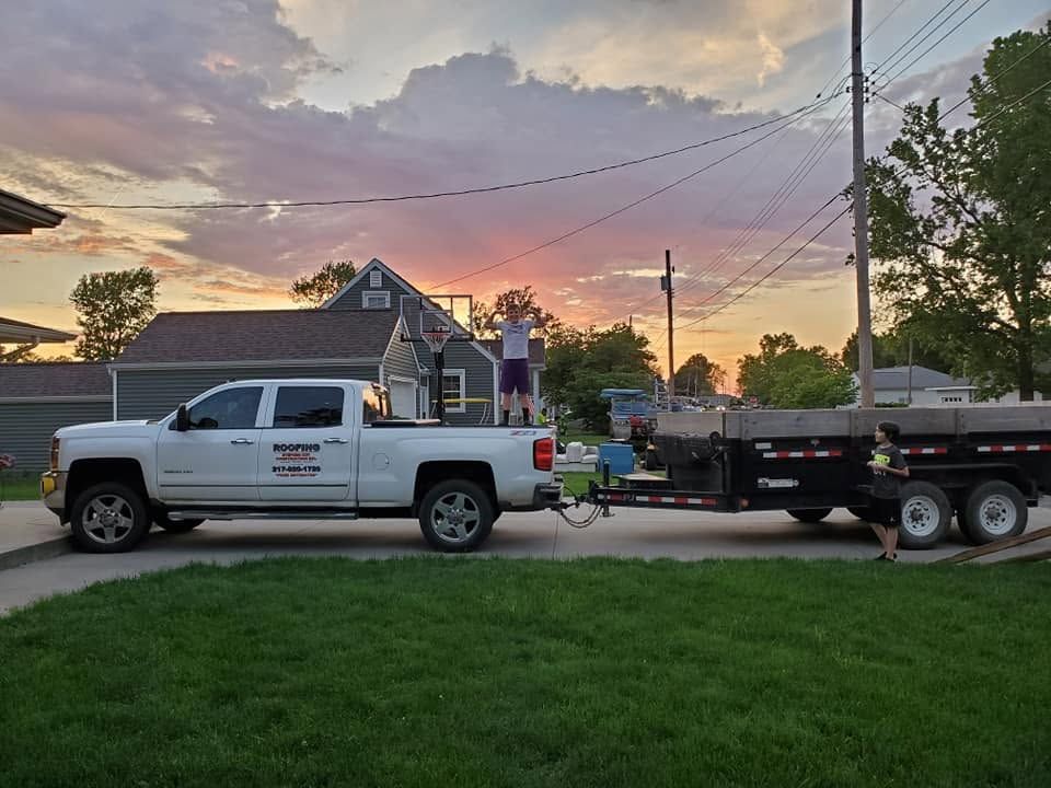 White pickup truck towing a flatbed trailer at sunset on a residential street
