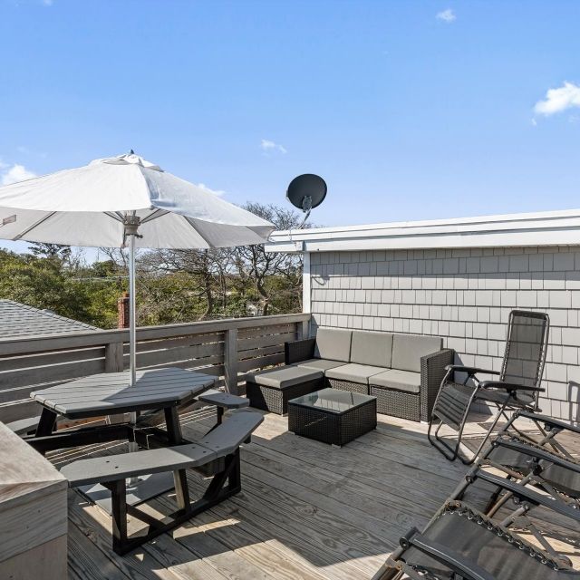 A rooftop deck with a table and chairs under an umbrella