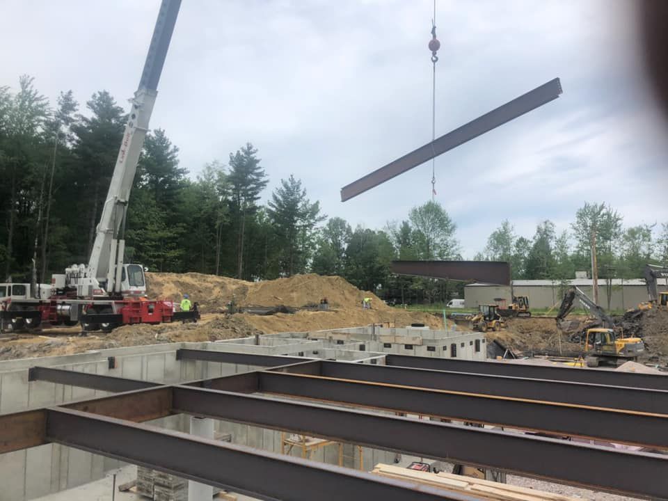 A Mayo Crane Rental lowers a steel beam into place on a construction site