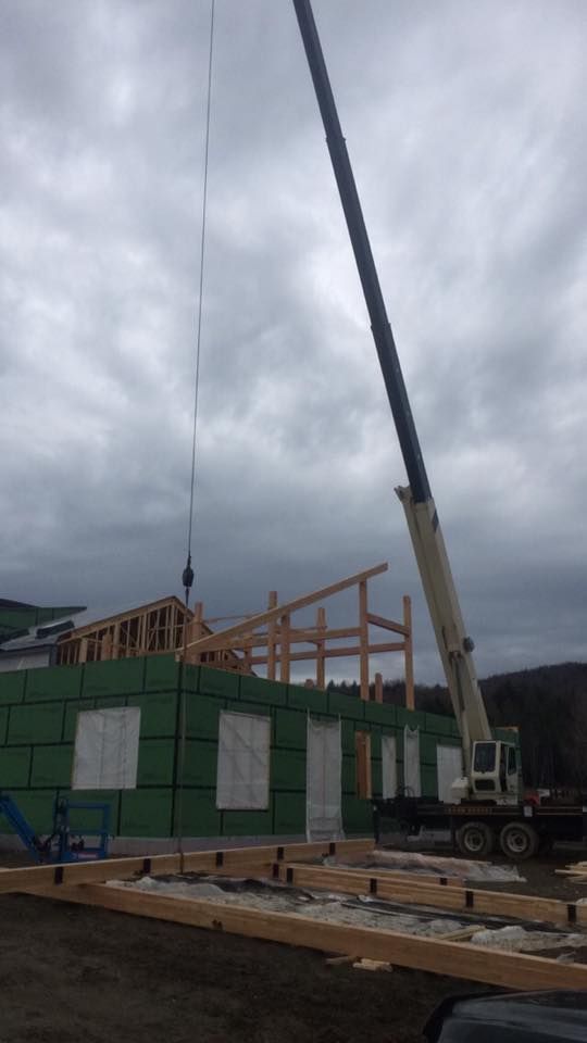 A commercial structure is built with the assistance of a crane rented in Vermont