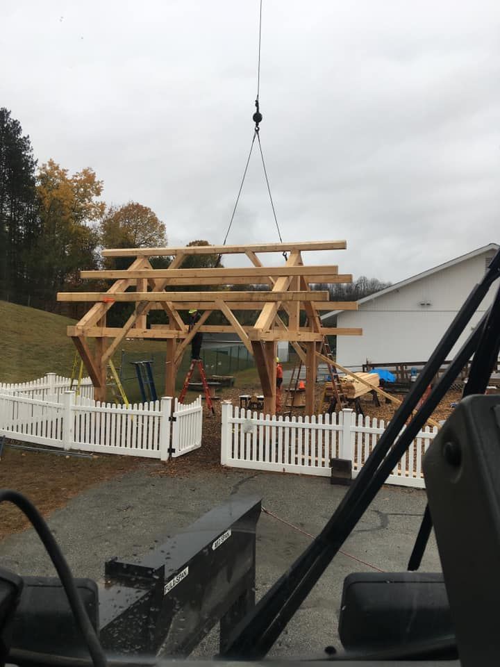 A roofing structure is raised by a Mayo Crane Rental on a construction site in Vermont