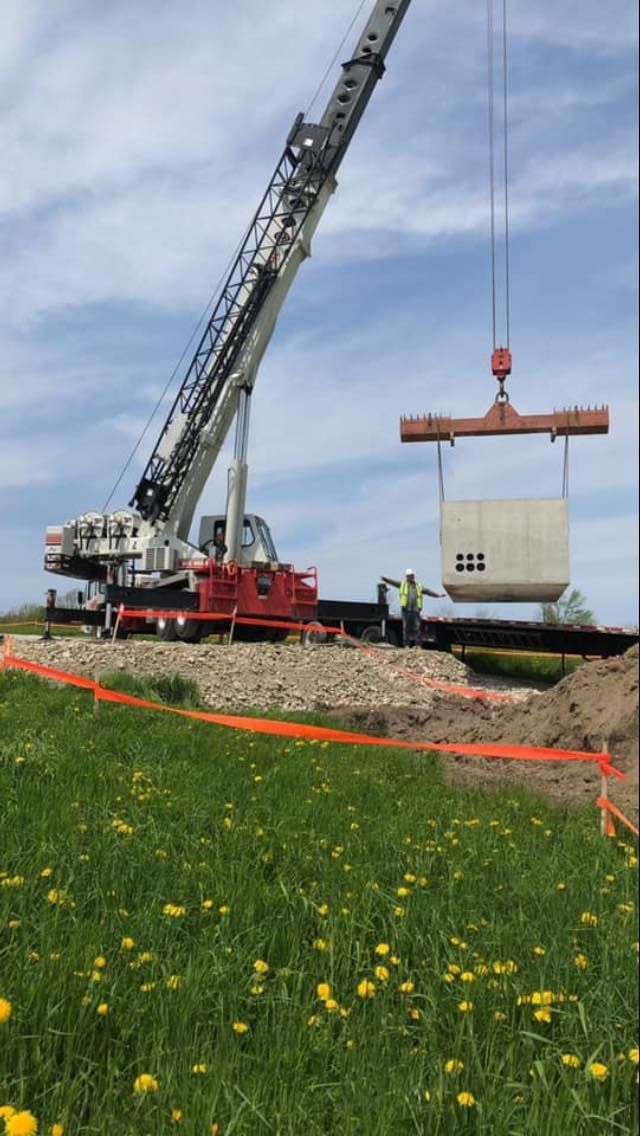 A crane rented from Mayo Crane Rental, LLC lifts a cement pillar on a construction site