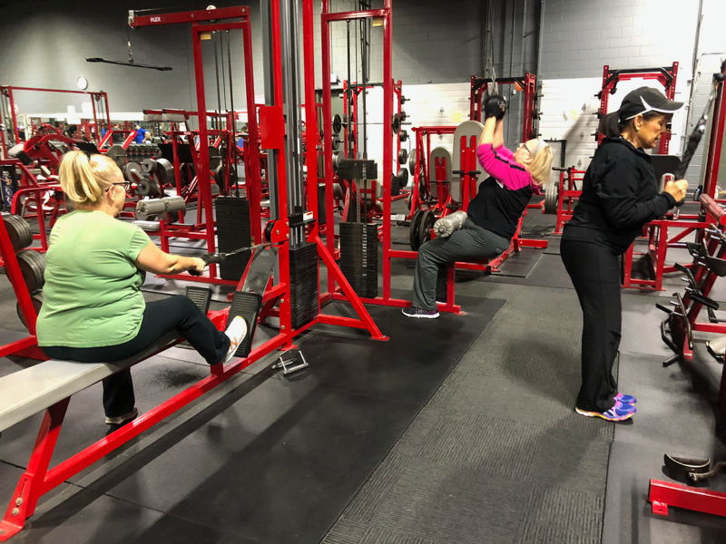 A man in a green shirt is lifting a barbell in a gym