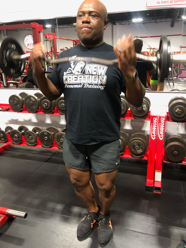 A man is lifting a barbell in a gym.