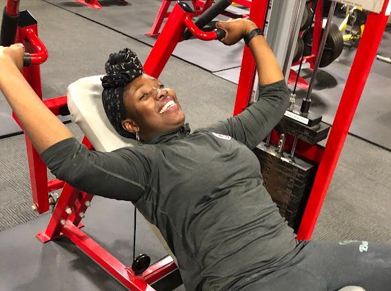 A woman is smiling while using a machine in a gym.