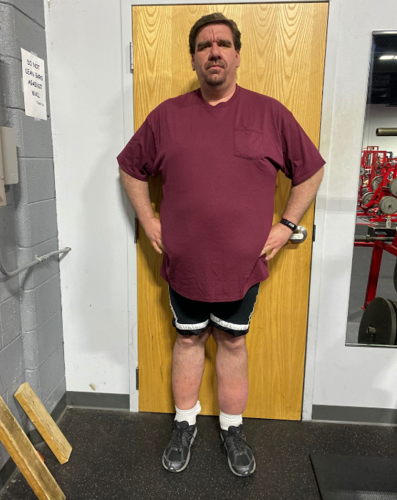A man in a maroon shirt is standing in front of a door