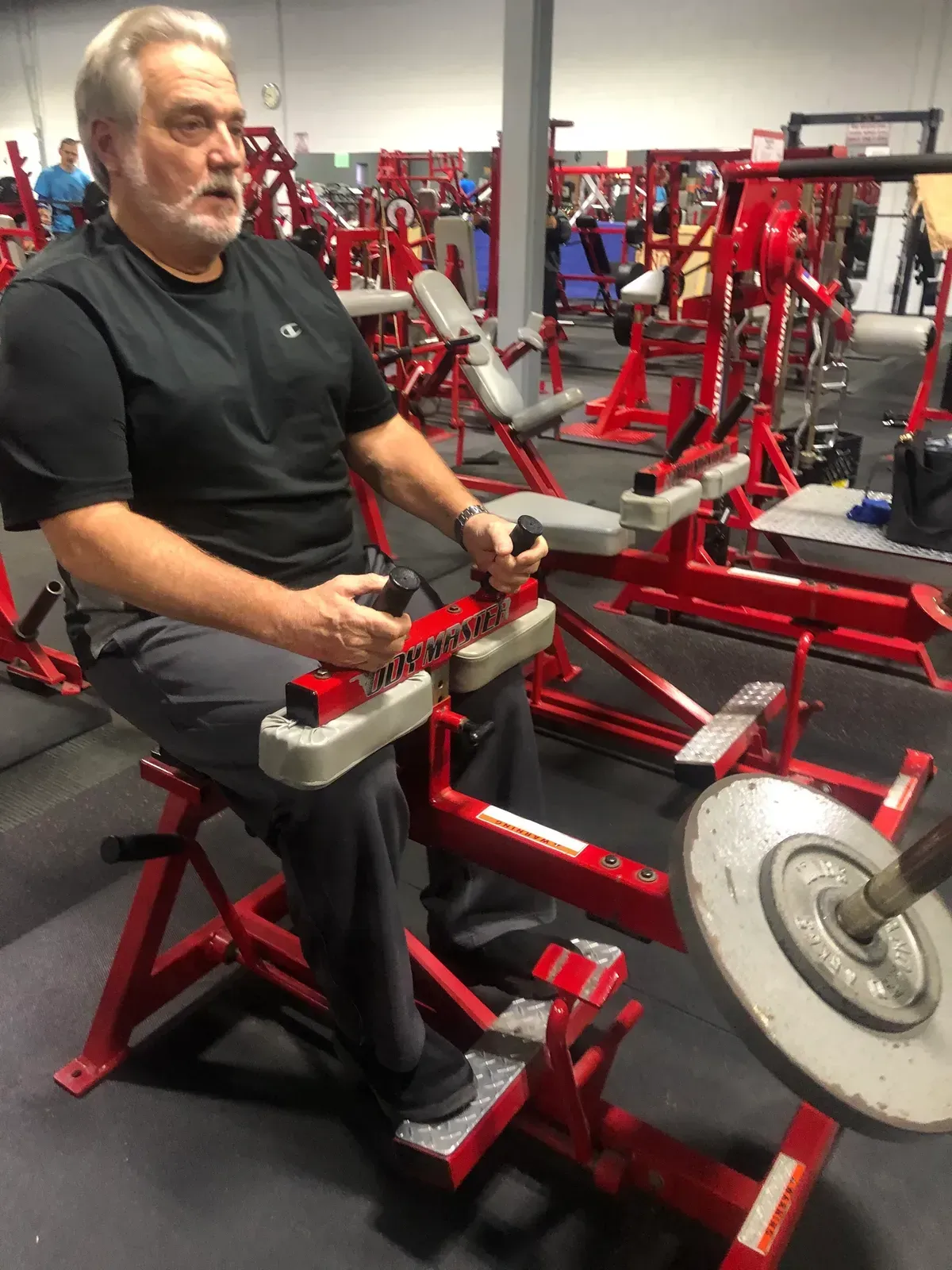 A man is sitting on a machine in a gym