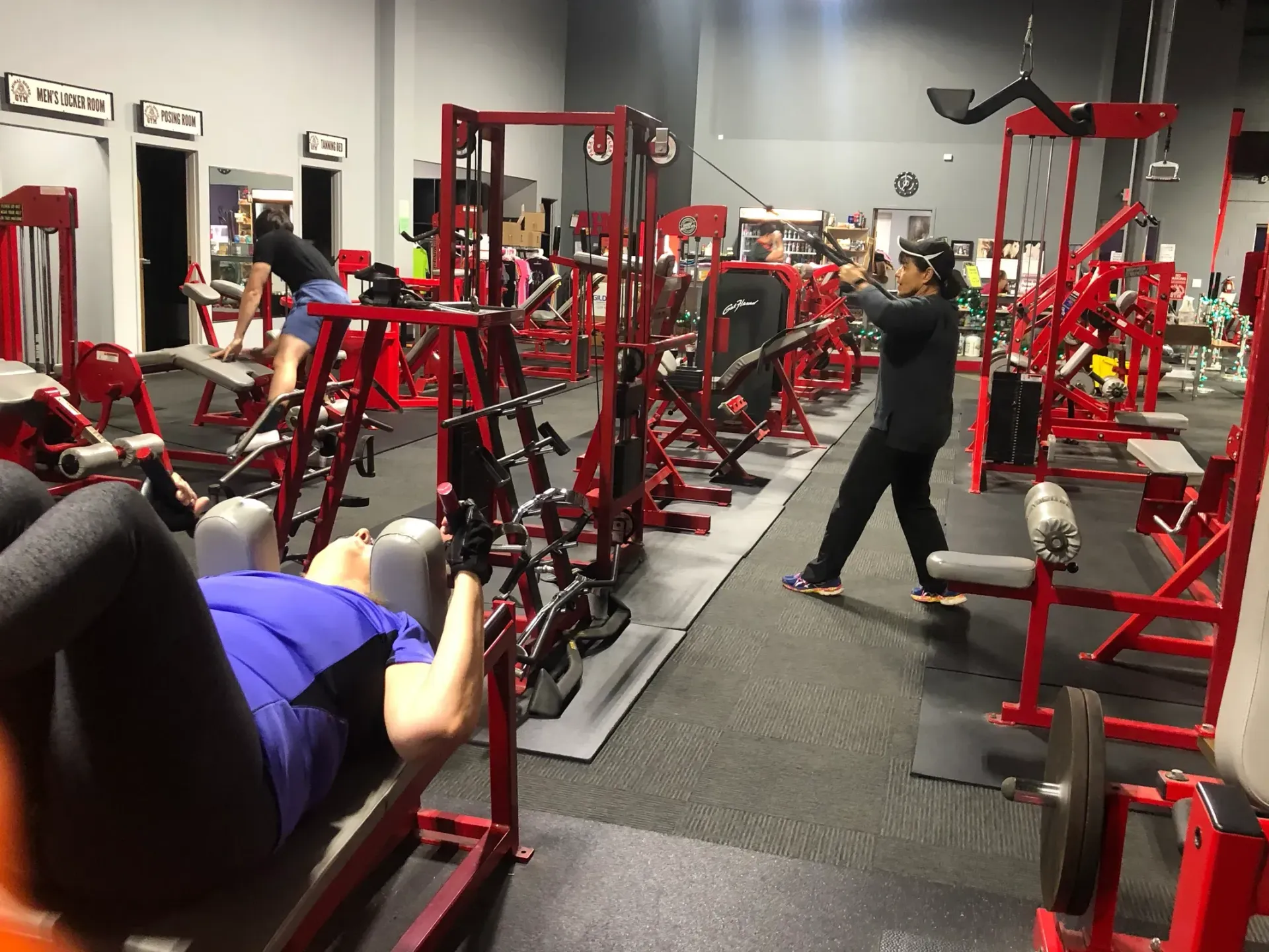 A man is standing in a gym with a lot of red exercise equipment.