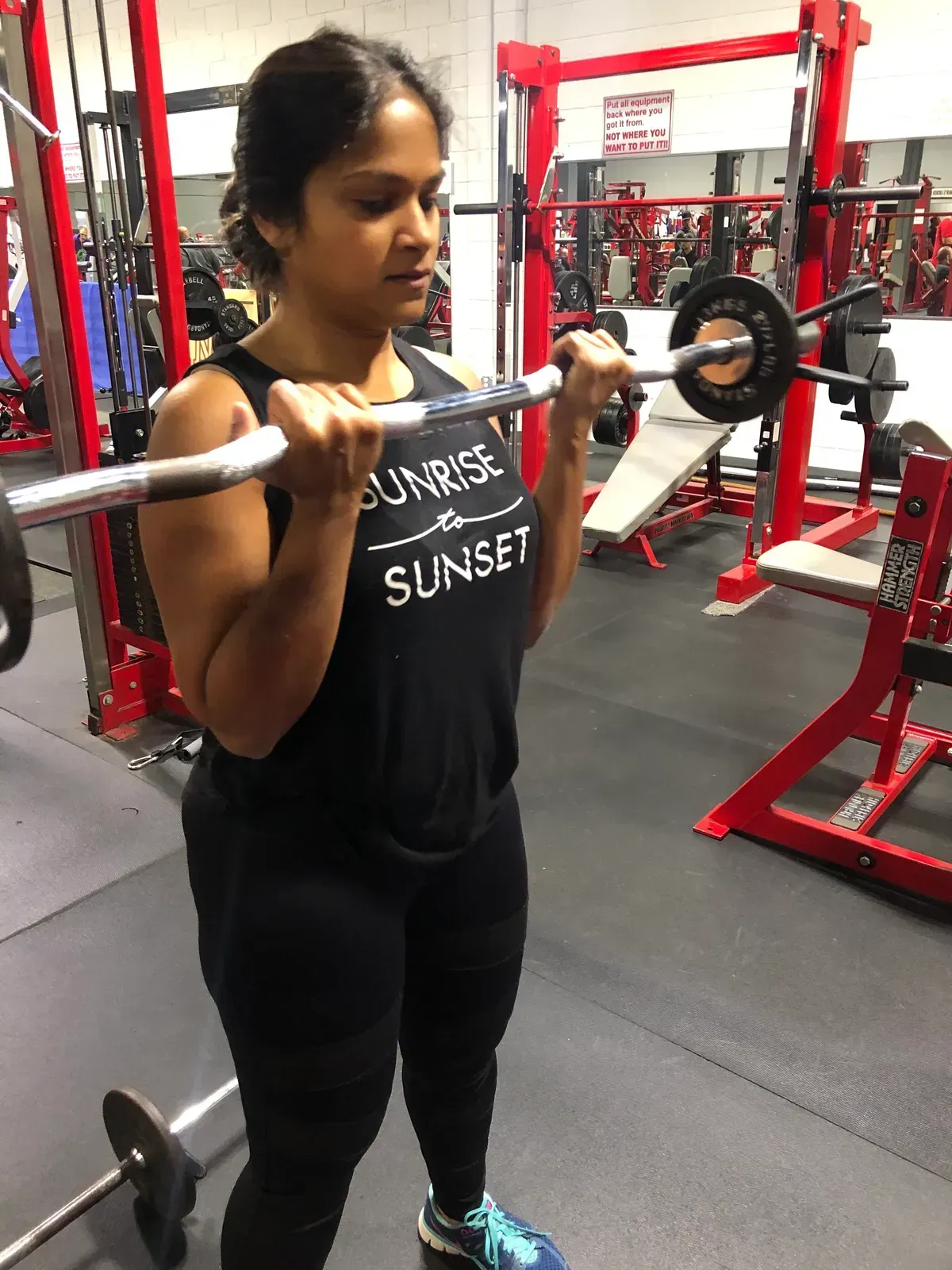 A woman is lifting a barbell in a gym.