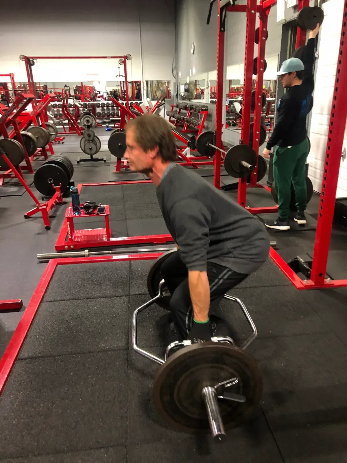 A man is squatting down with a barbell in a gym