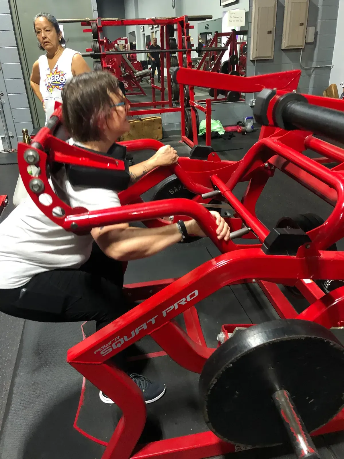 A woman is squatting on a machine in a gym