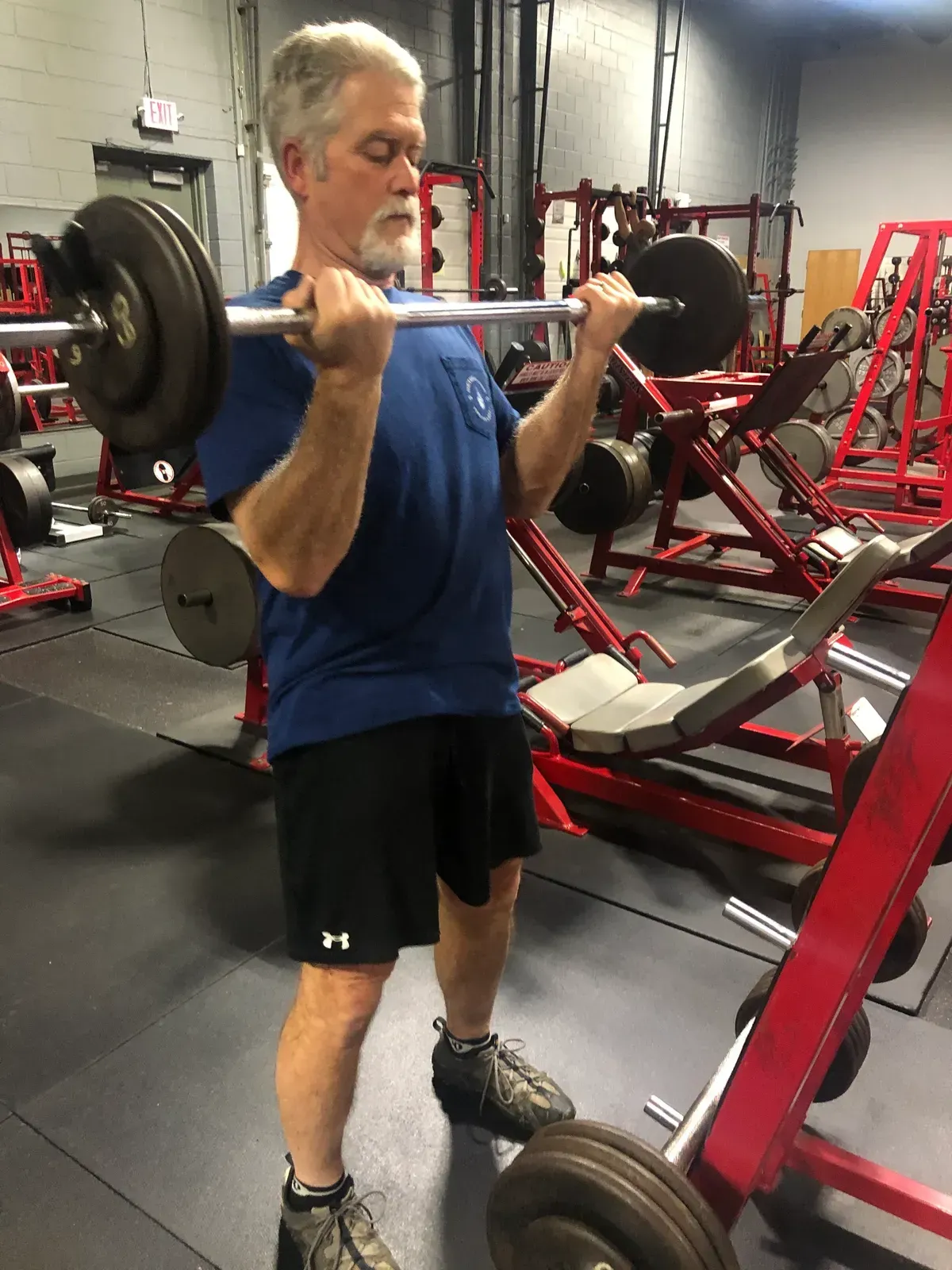 A man is lifting a barbell in a gym.