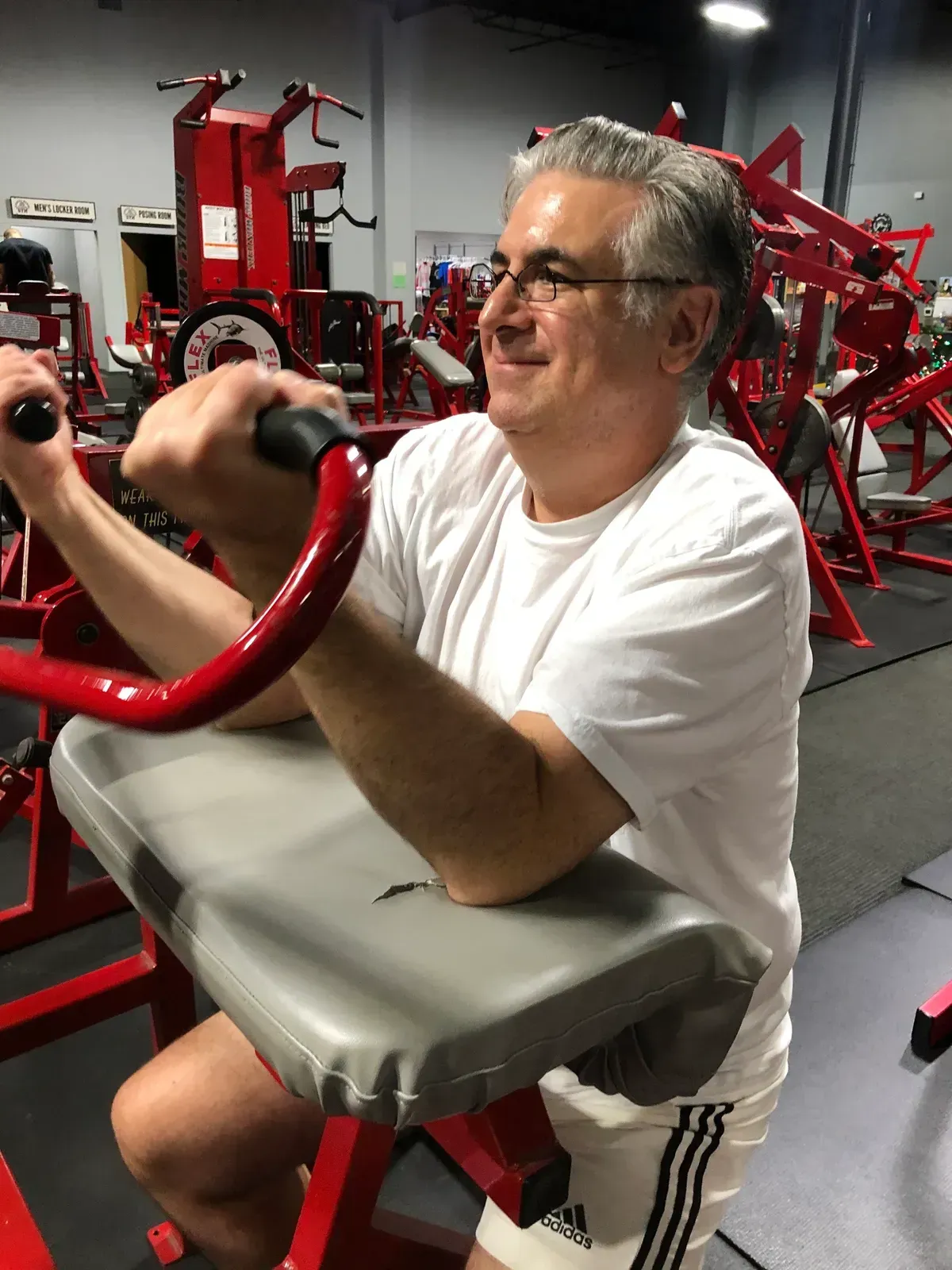 A man in a white shirt is using a machine in a gym