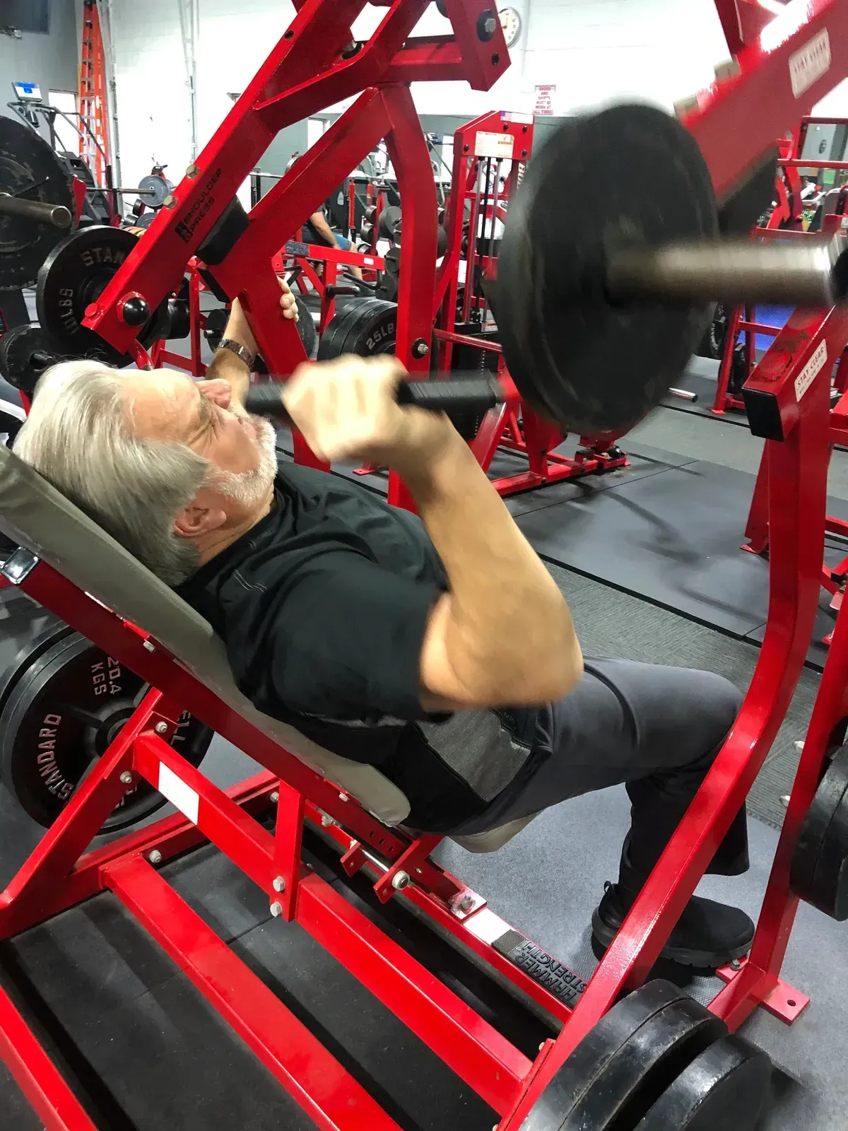 A man is lifting a barbell in a gym