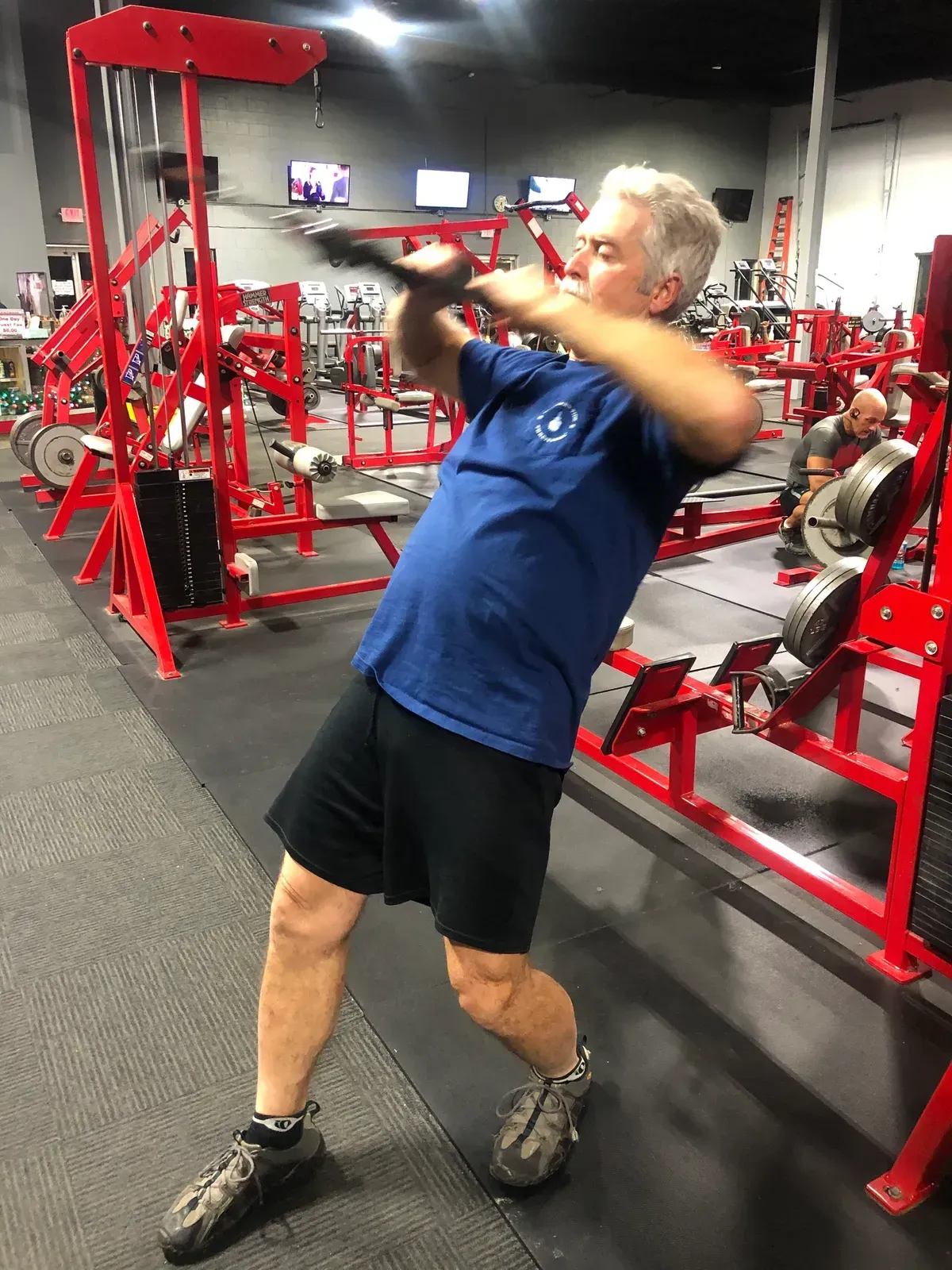 A man in a blue shirt is using a machine in a gym.