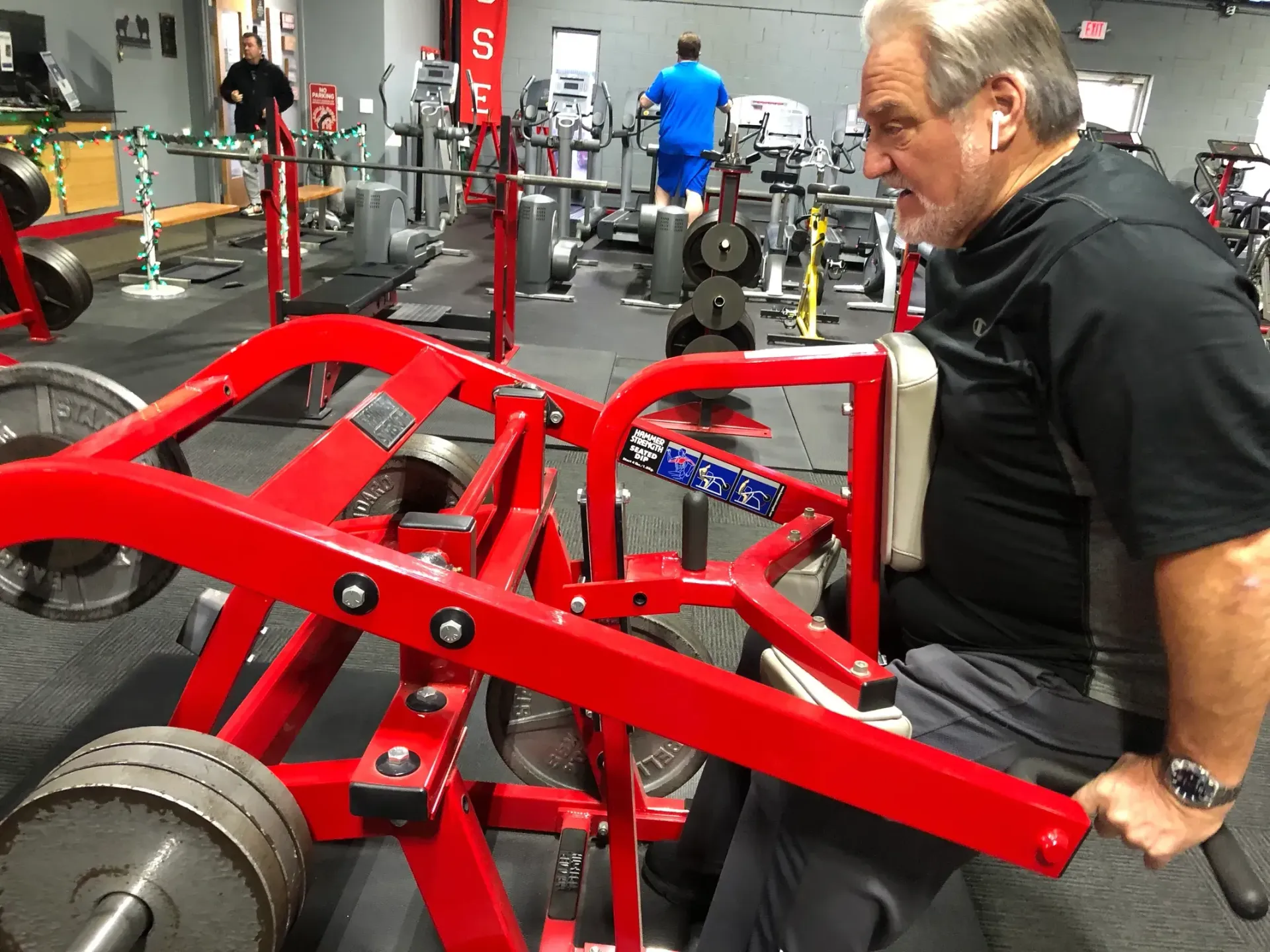 A man is sitting on a machine in a gym.