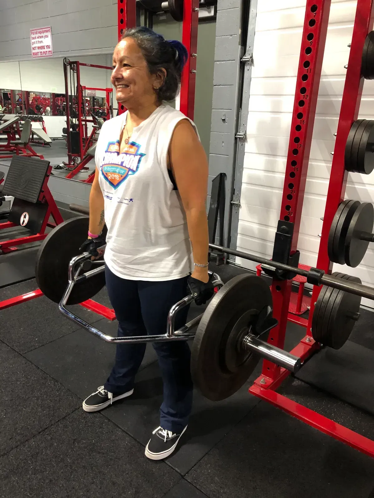 A woman is lifting a barbell in a gym.