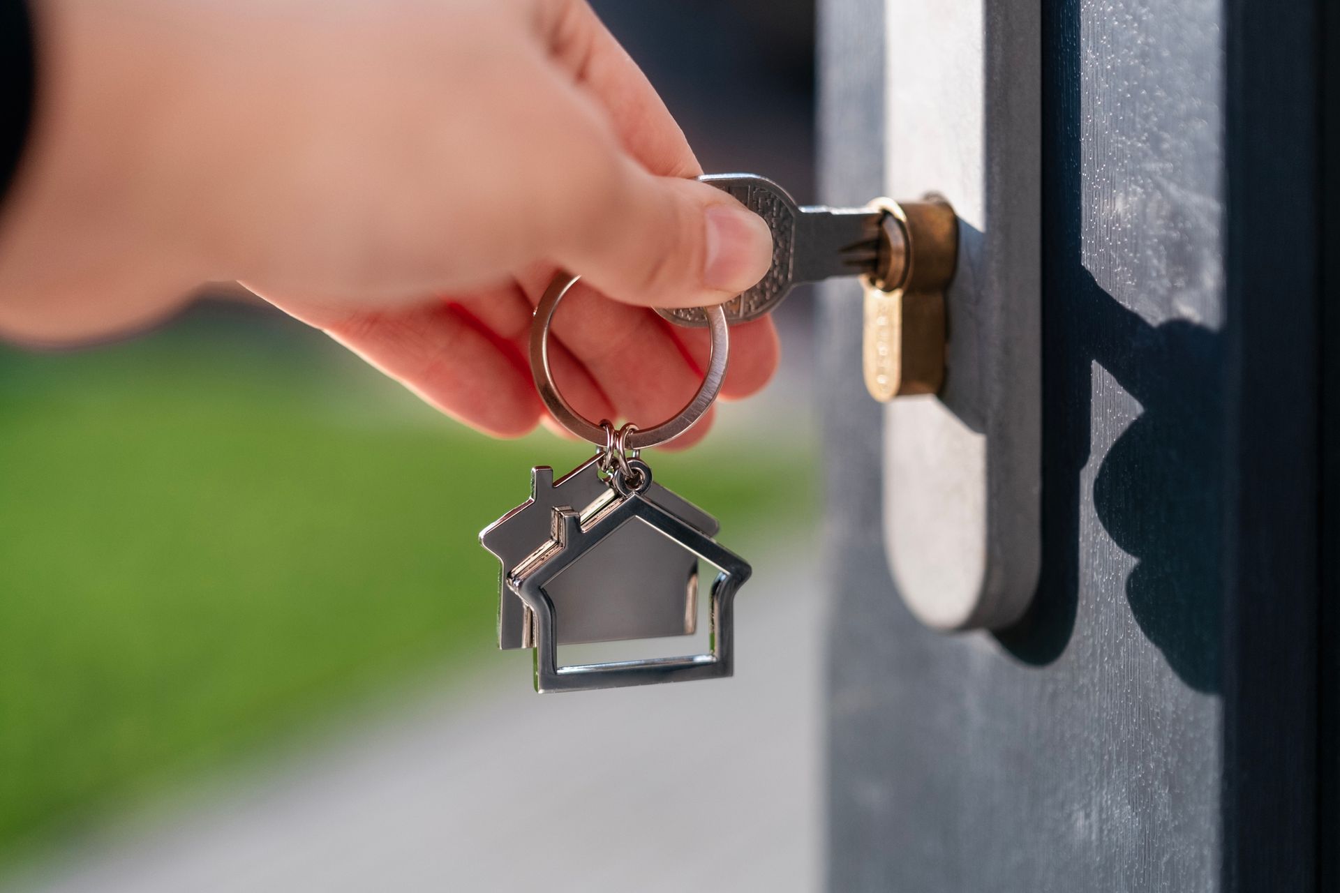 A person is holding a key with a house keychain attached to it.